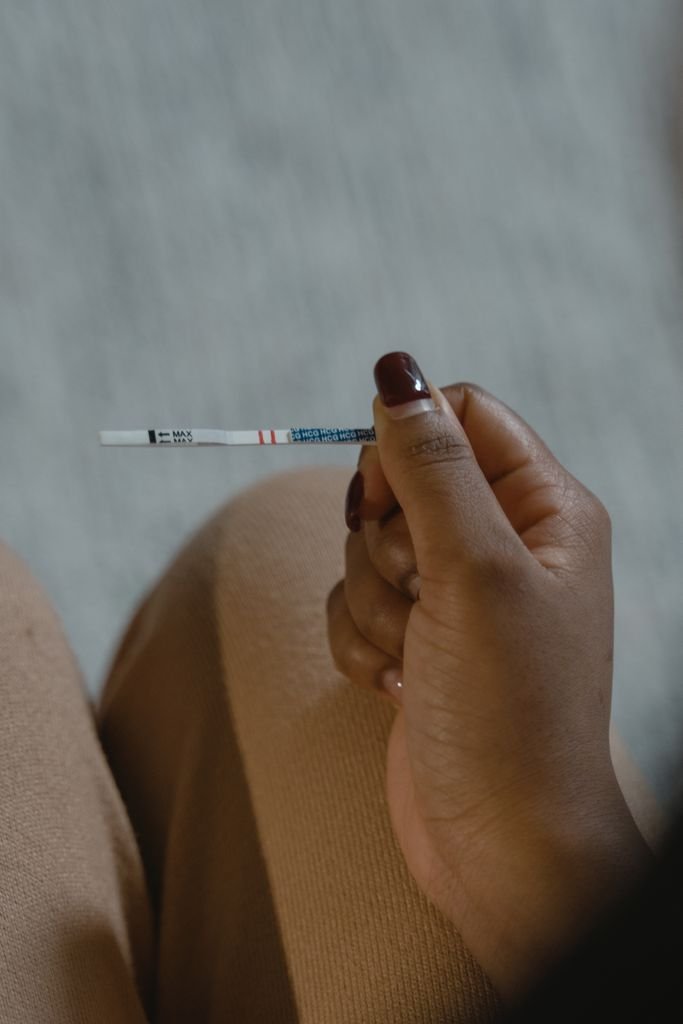 A close-up shot of a hand holding a pregnancy test with a blurred background, indicating pregnancy result analysis.